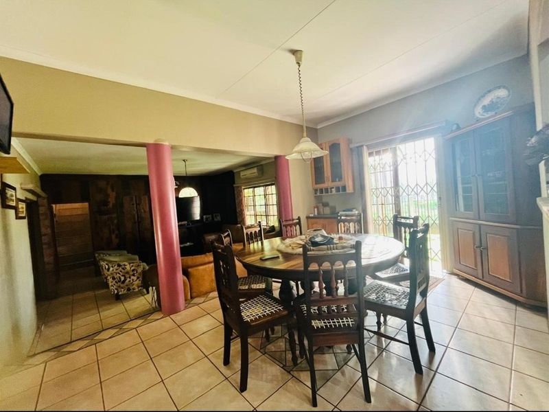 Open-plan dining and living area featuring tiled flooring, structural support columns, and sliding door access to the exterior.
