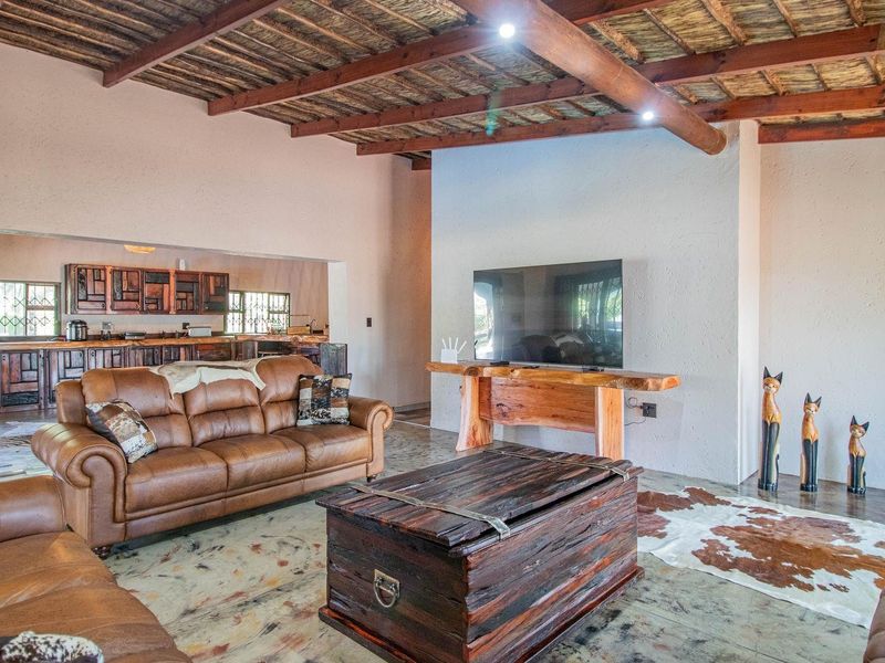 Spacious open-plan living area featuring exposed timber beam ceilings, textured walls, and a seamless transition to the adjacent kitchen space.