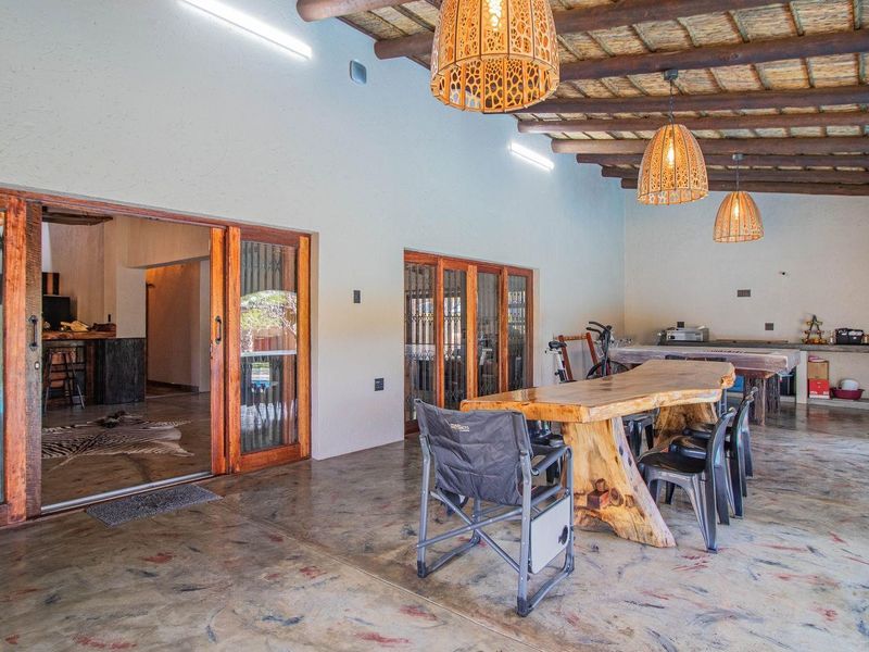 Spacious covered patio featuring a rustic timber ceiling, polished concrete flooring, and a built-in outdoor kitchen area with sink and counter space.