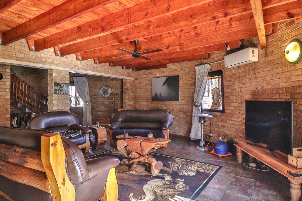 Rustic living room featuring exposed brick walls, a timber beam ceiling, tiled flooring, and a wall-mounted air conditioning unit.