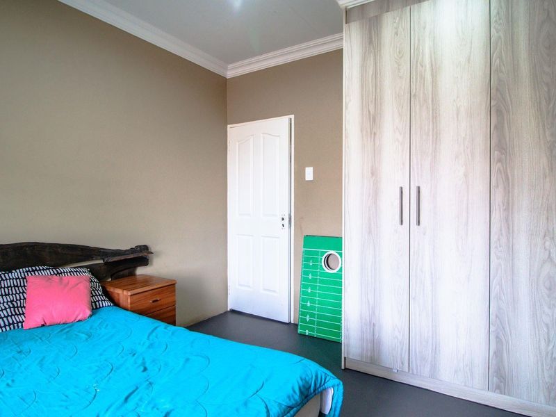 A well-maintained bedroom featuring neutral wall tones, crown molding, and large built-in wooden wardrobes providing ample storage space.