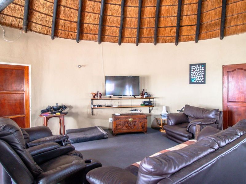 A circular living room featuring a traditional thatched roof with exposed timber rafters and solid wooden doors.