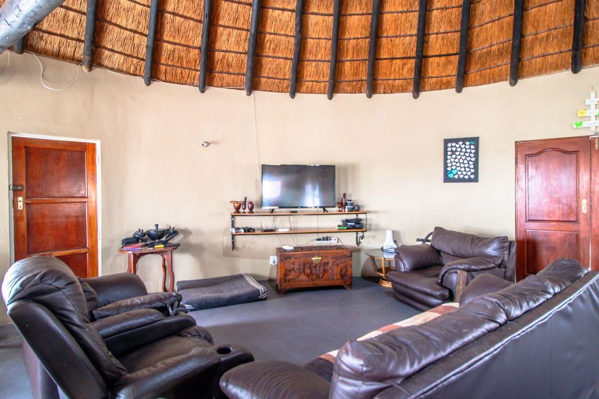A circular living room featuring a traditional thatched roof with exposed timber rafters and solid wooden doors.