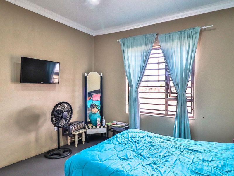 A functional bedroom featuring neutral wall tones, a window with security bars, and crown molding.