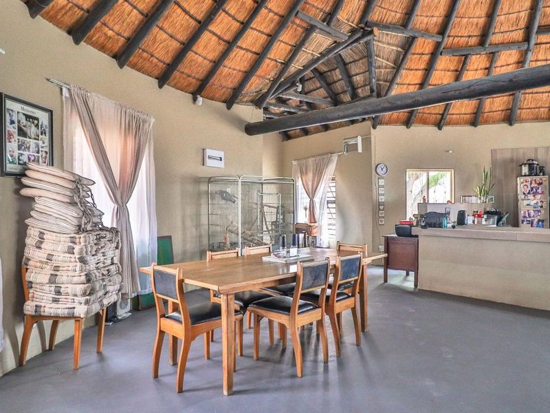 Open-plan living and dining area featuring a traditional thatched roof with exposed timber beams and a built-in kitchen counter.