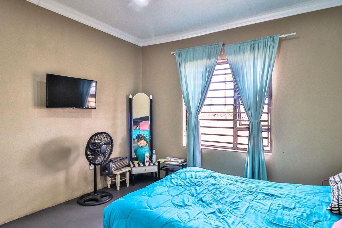 A functional bedroom featuring neutral wall tones, a window with security bars, and crown molding.