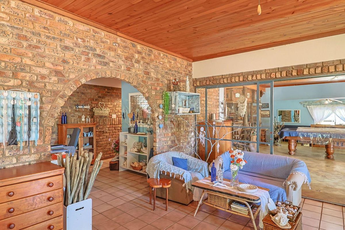 Spacious living area featuring exposed brick walls, arched architectural detailing, and a warm timber-paneled ceiling, connecting to an adjacent games room.