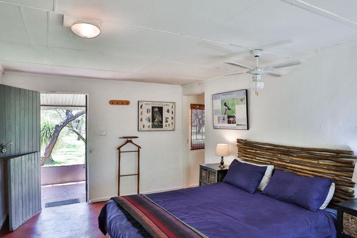 A rustic bedroom featuring a ceiling fan, tiled flooring, and direct access to an outdoor patio area.