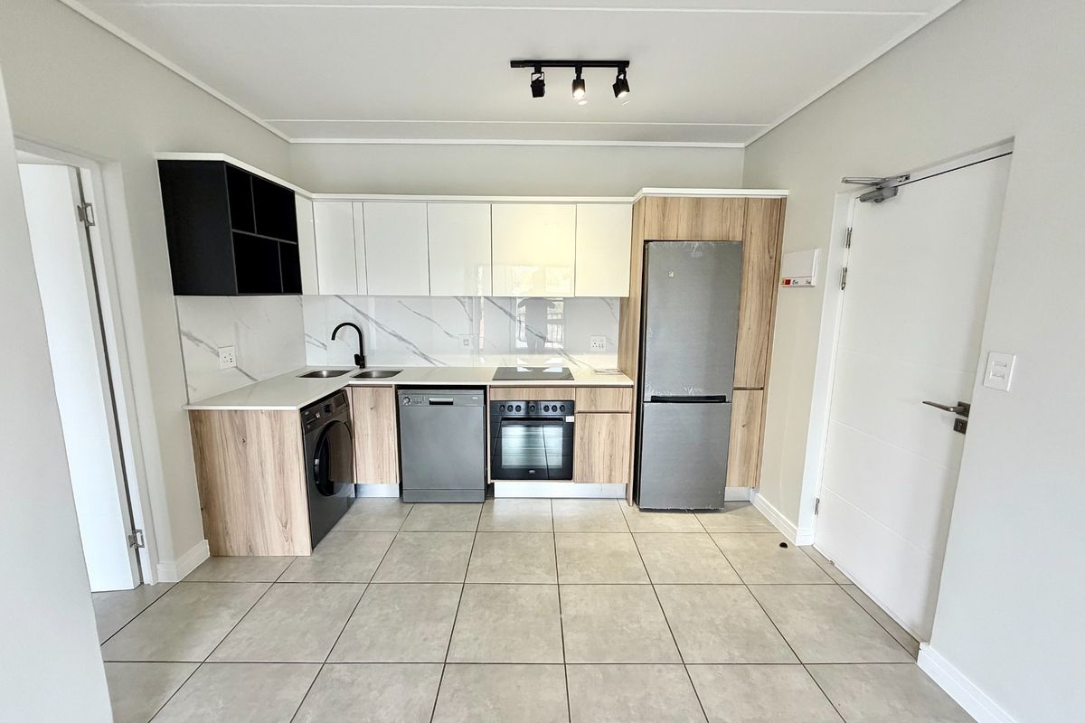 Modern kitchen featuring sleek two-tone cabinetry, stone countertops, marble-look splashback, and integrated appliances, finished with neutral floor tiles.