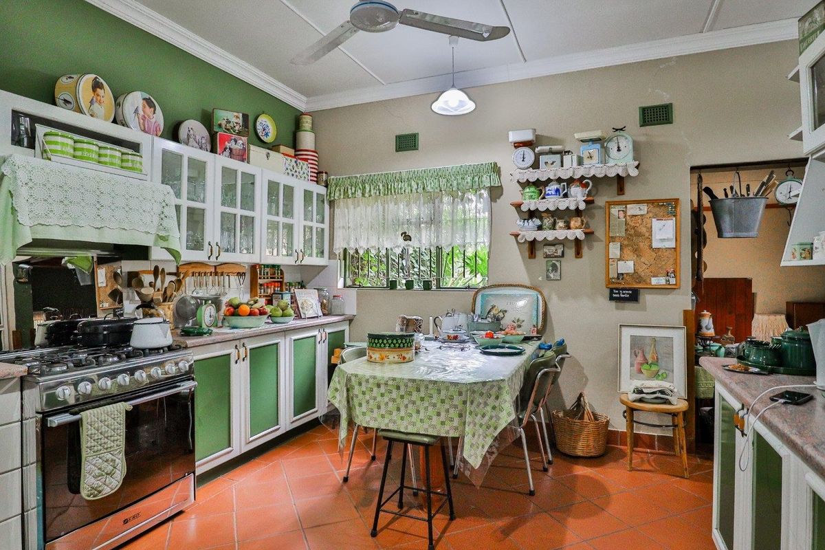 A traditional kitchen featuring built-in cabinetry, a gas stove with extractor fan, and terracotta floor tiles, offering a functional and classic farmhouse aesthetic.