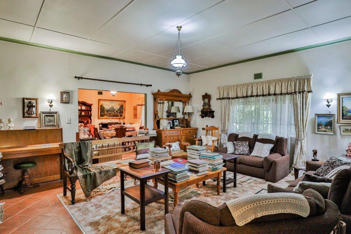 Spacious living room featuring traditional architectural details, including a tiled floor and a large opening leading to the adjacent dining area.