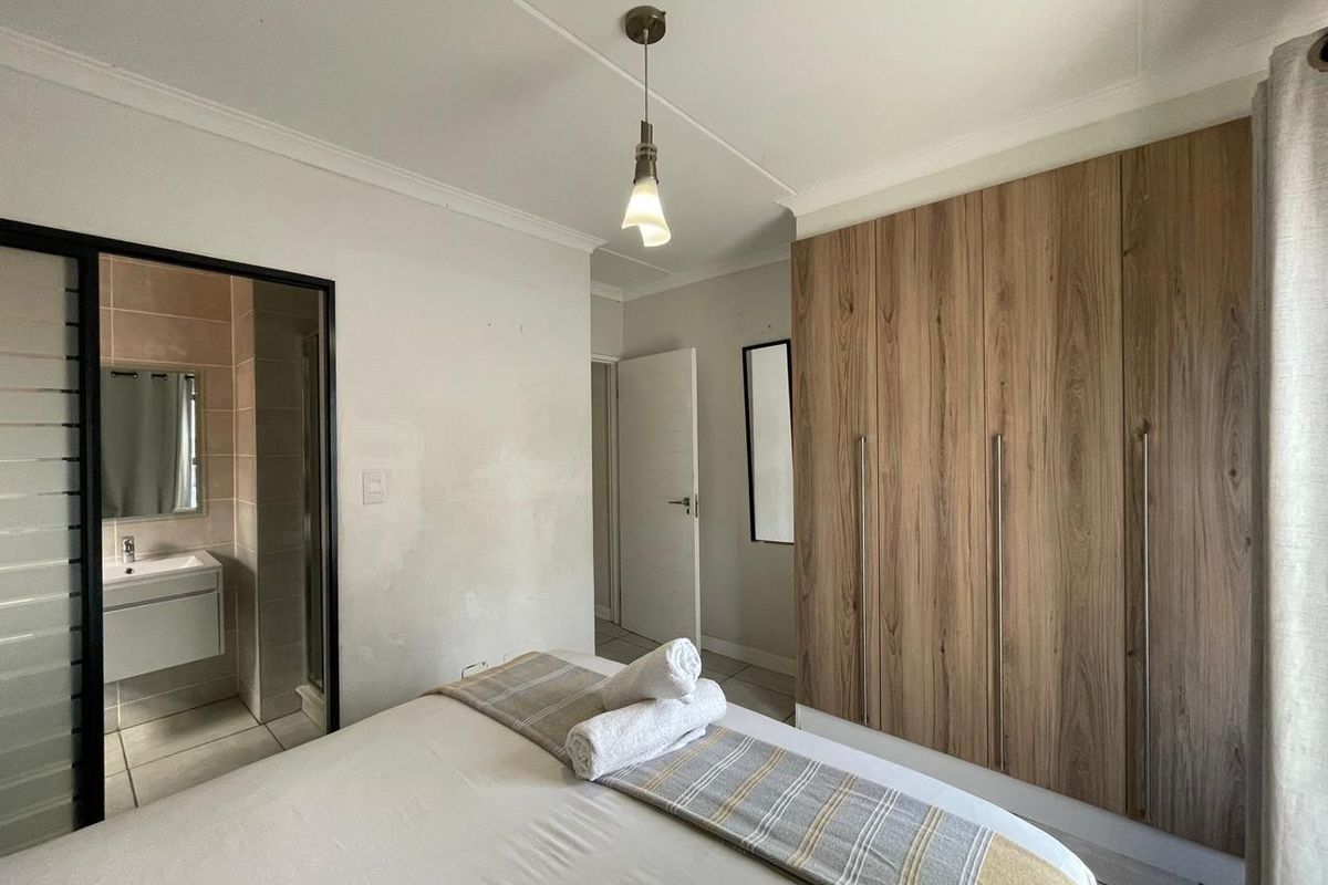 Bedroom featuring built-in wood-finish wardrobes and an en-suite bathroom with a modern vanity.
