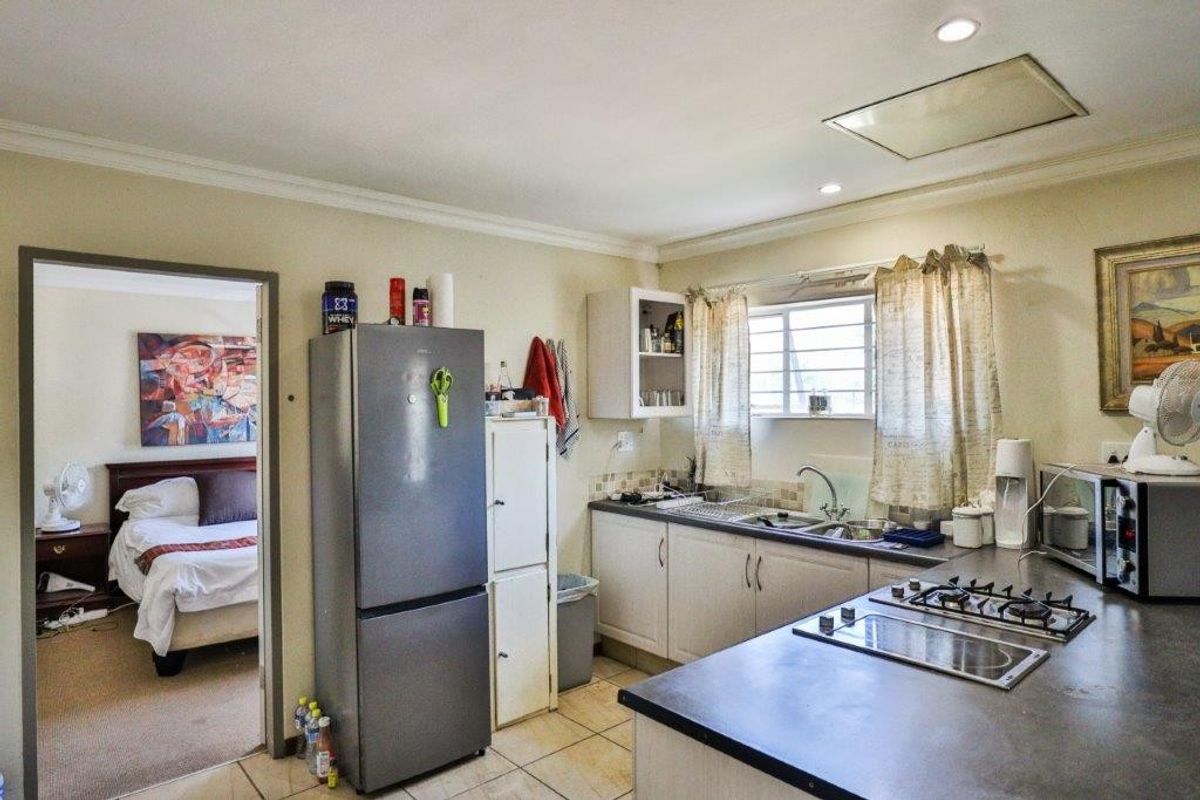 A functional kitchen featuring built-in cabinetry, a gas hob, and a double sink, with an adjacent view into a bedroom.