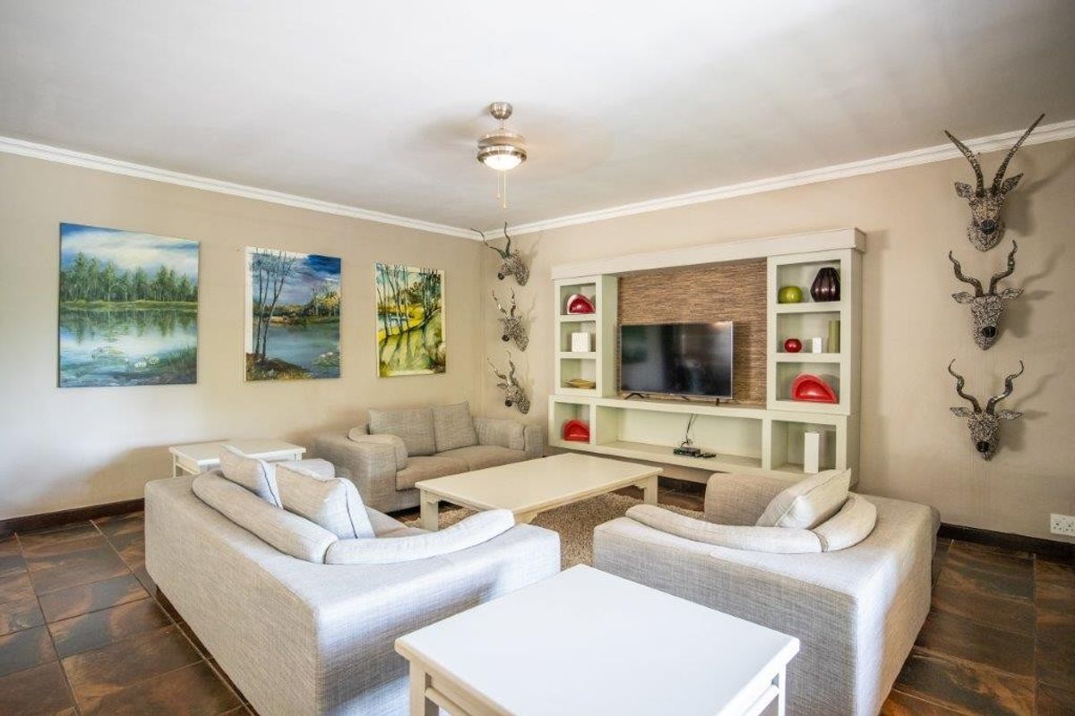 A comfortable living room featuring a built-in entertainment unit with shelving and tiled flooring.