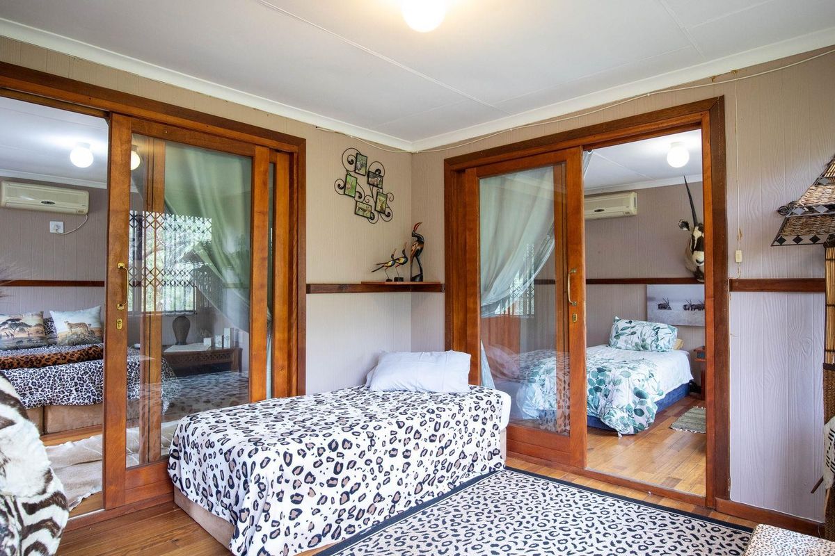 A living area featuring wooden sliding doors that open into two adjacent bedrooms, each equipped with wall-mounted air conditioning units.