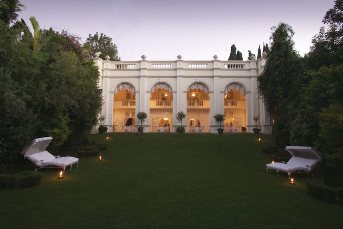 A grand rear elevation featuring an elegant arched colonnade, a classic balustrade, and a beautifully manicured lawn.