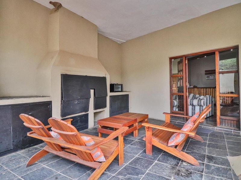 Covered patio area featuring a built-in brick fireplace and dark slate flooring, providing a functional outdoor entertainment space with direct access to the interior.