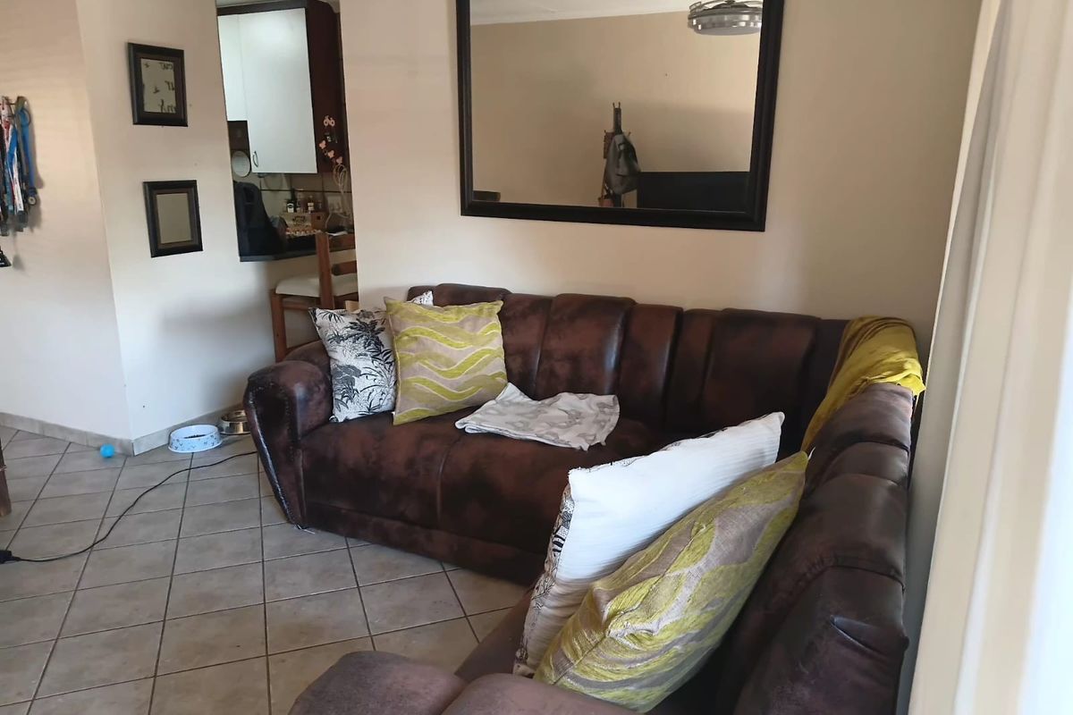 A view of the living area featuring tiled flooring and a glimpse into the adjacent kitchen space.