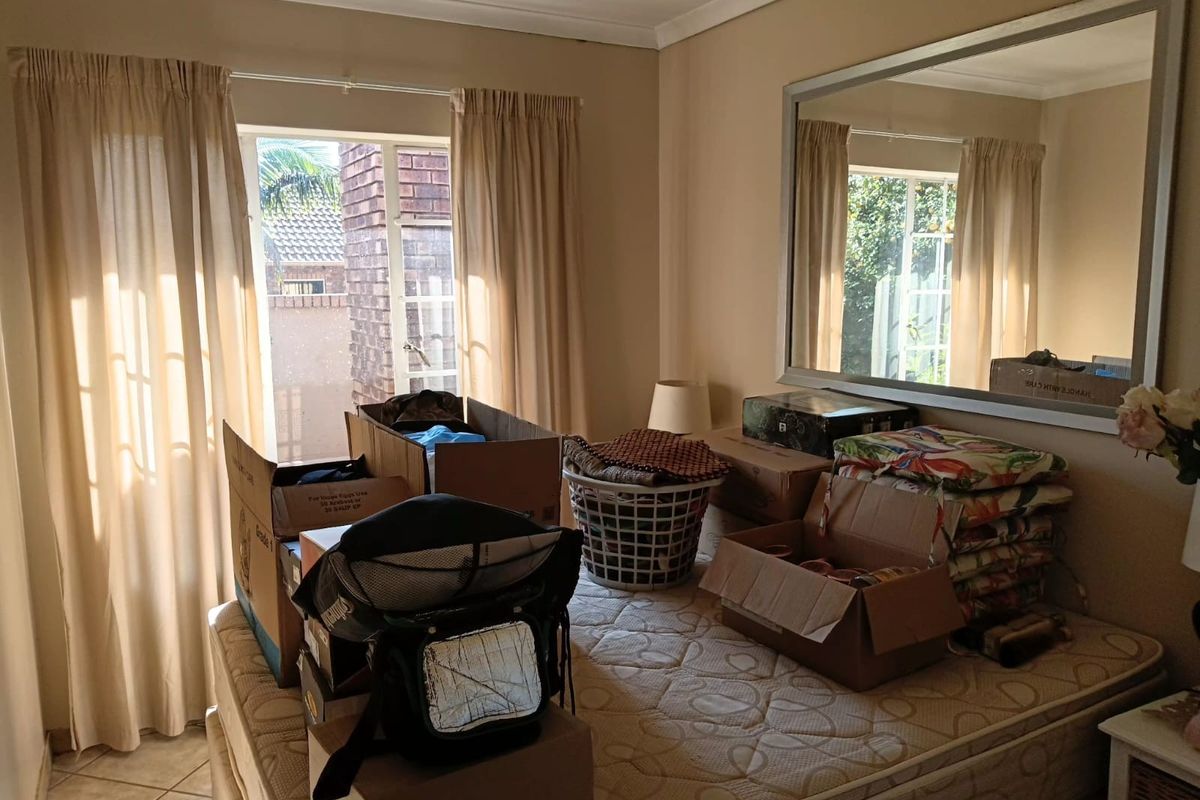 A bedroom featuring tiled flooring, a large wall-mounted mirror, and access to an outdoor area through a glass door with curtains.