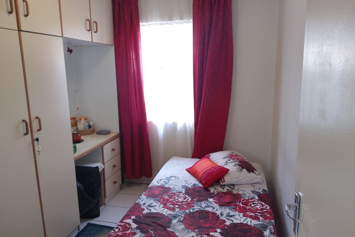 A compact bedroom featuring built-in cabinetry with integrated desk space and tiled flooring.
