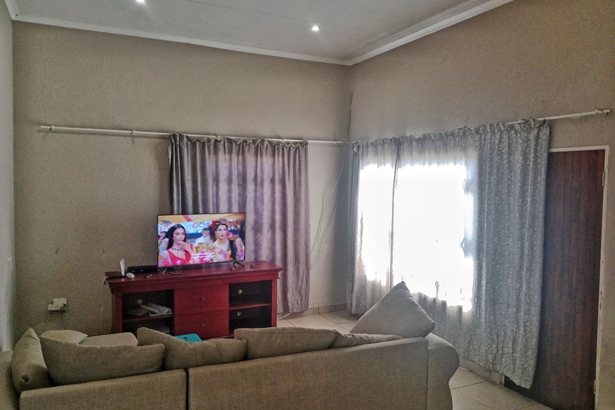 A living room featuring tiled flooring, recessed downlighting, and dual window treatments with curtain rods.