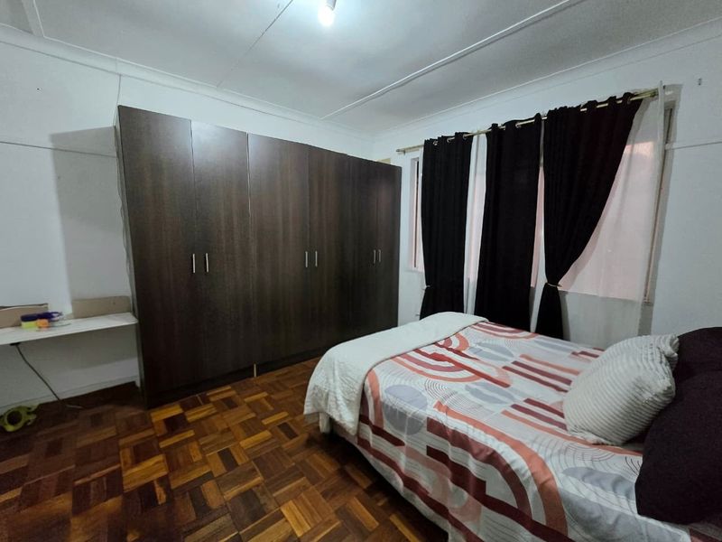 A bedroom featuring classic parquet flooring and a large, dark wood built-in wardrobe providing ample storage space.