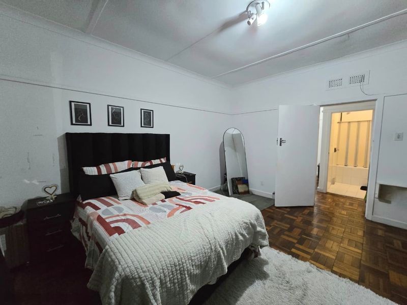 A bedroom featuring classic parquet flooring, a picture rail, and direct access to an en-suite bathroom.