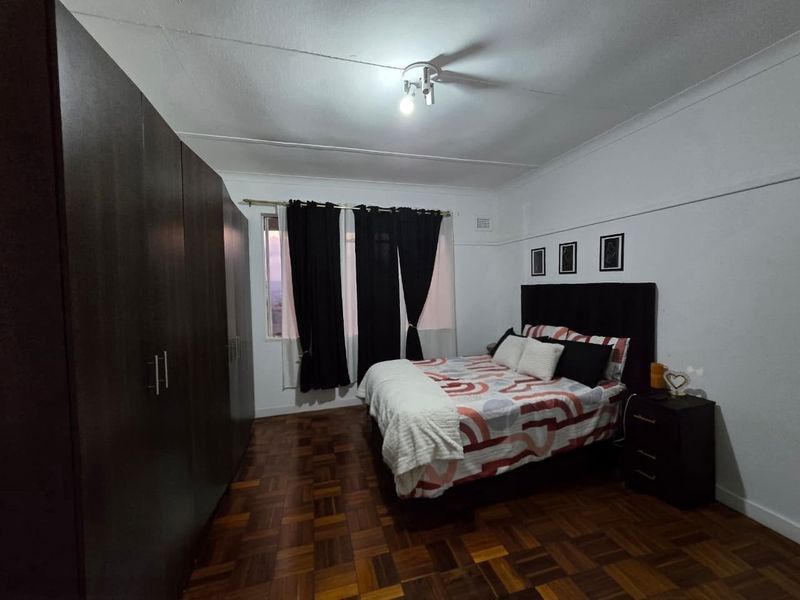 A bedroom featuring dark built-in cupboards and classic parquet flooring, offering a functional space with potential for modern updates.