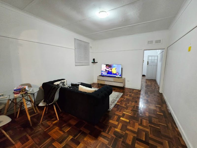 A living room featuring classic parquet flooring, white walls, and a coved ceiling, providing a neutral foundation for interior design updates.