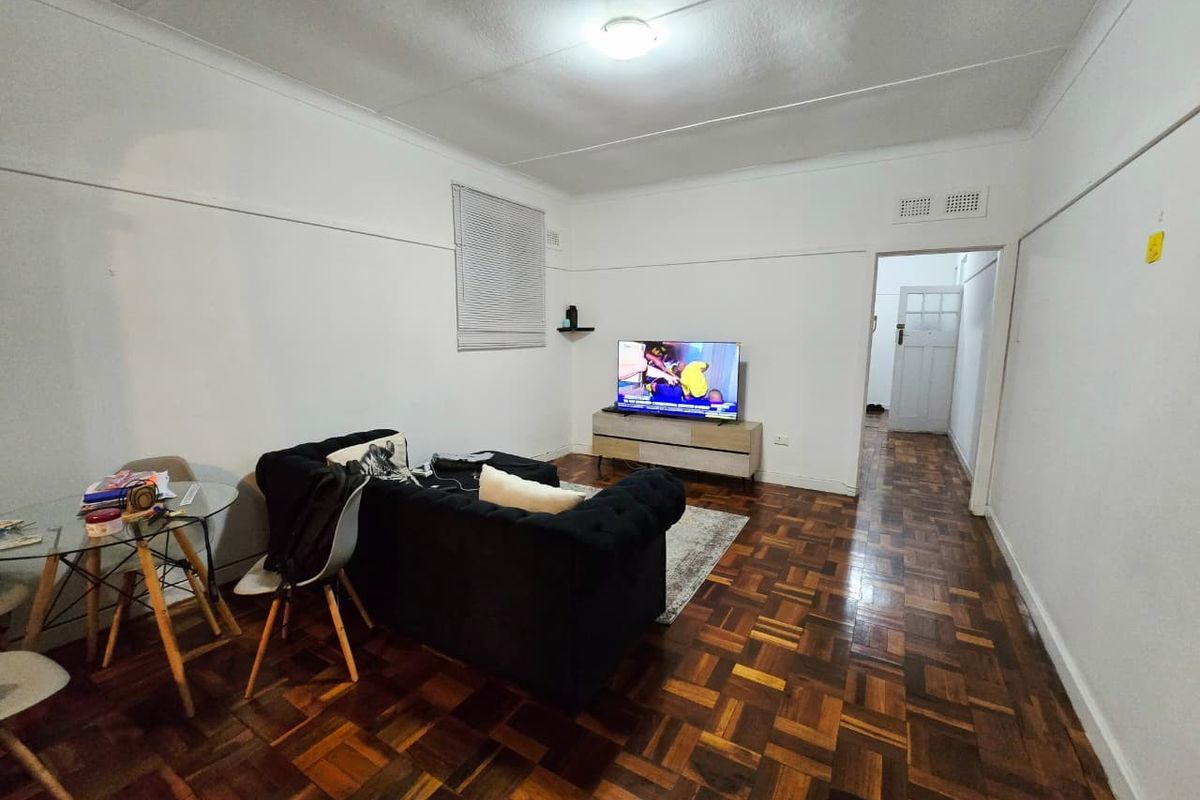 A living room featuring classic parquet flooring, white walls, and a coved ceiling, providing a neutral foundation for interior design updates.