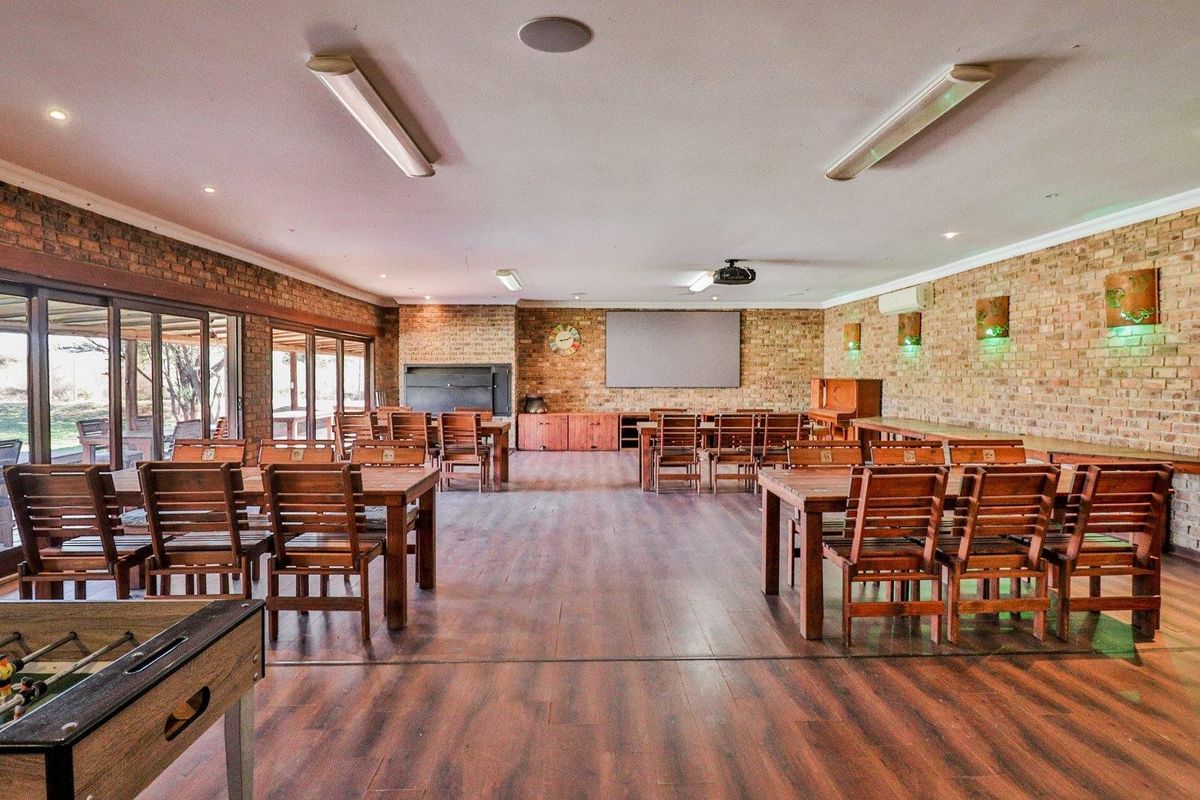 Spacious entertainment area featuring exposed brick walls, wood-look flooring, a built-in fireplace, and large sliding doors opening to the exterior.