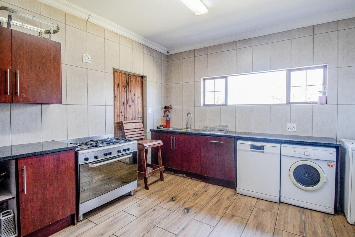 Functional kitchen featuring dark wood cabinetry, granite countertops, tiled walls, and space for integrated laundry appliances.