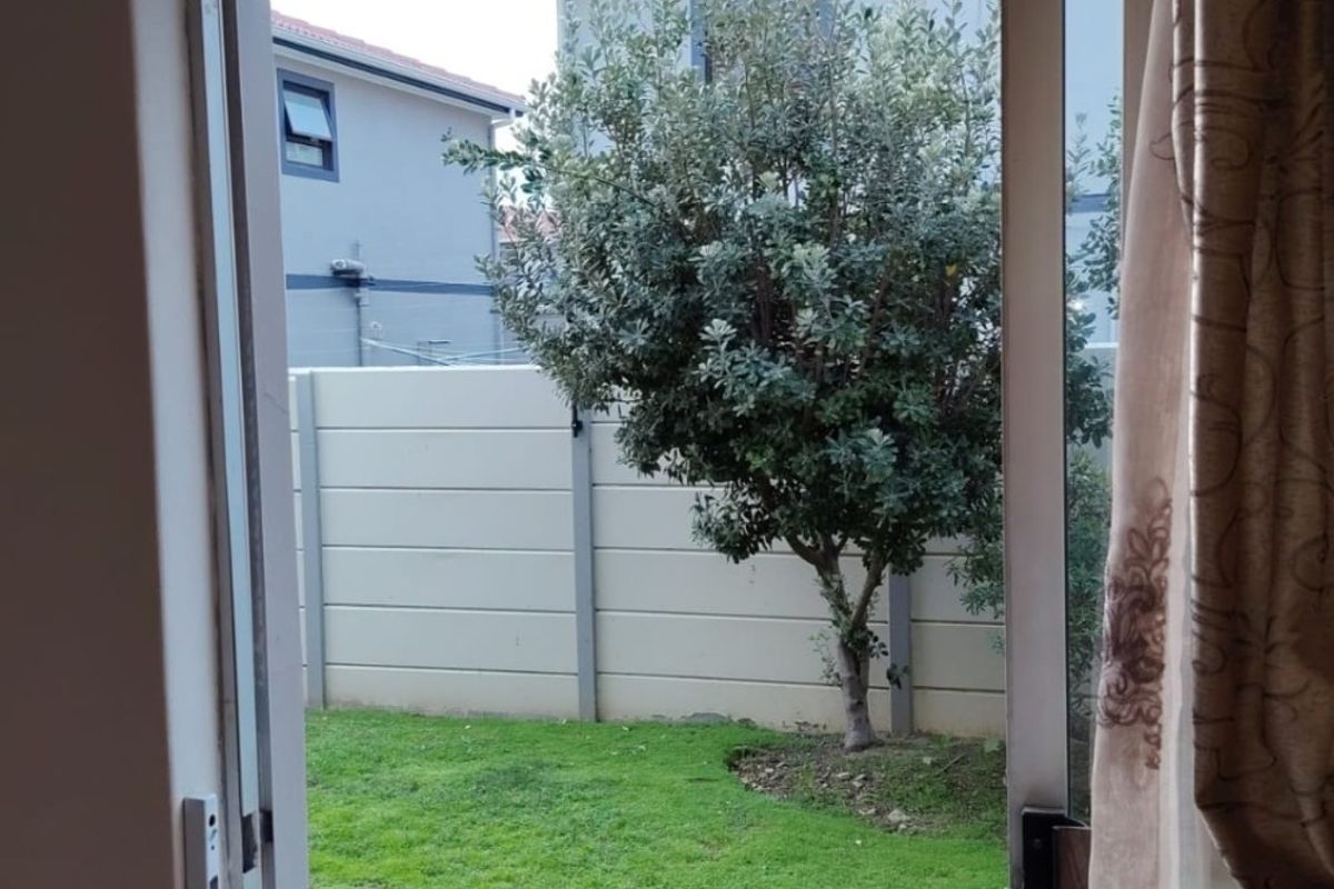 View from an interior doorway looking out onto a private rear garden with a lawn and boundary wall.