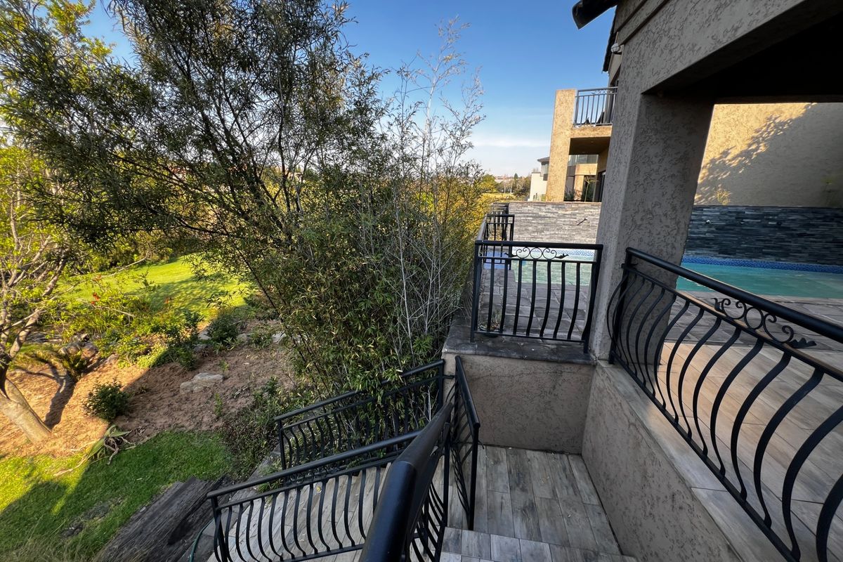 Outdoor staircase with decorative metal railings leading to a patio area featuring a swimming pool and views of the surrounding garden.
