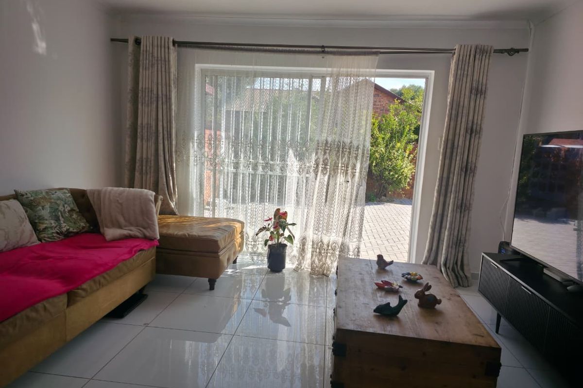 A living room featuring large sliding glass doors that provide access to the outdoor area, complemented by polished tiled flooring.