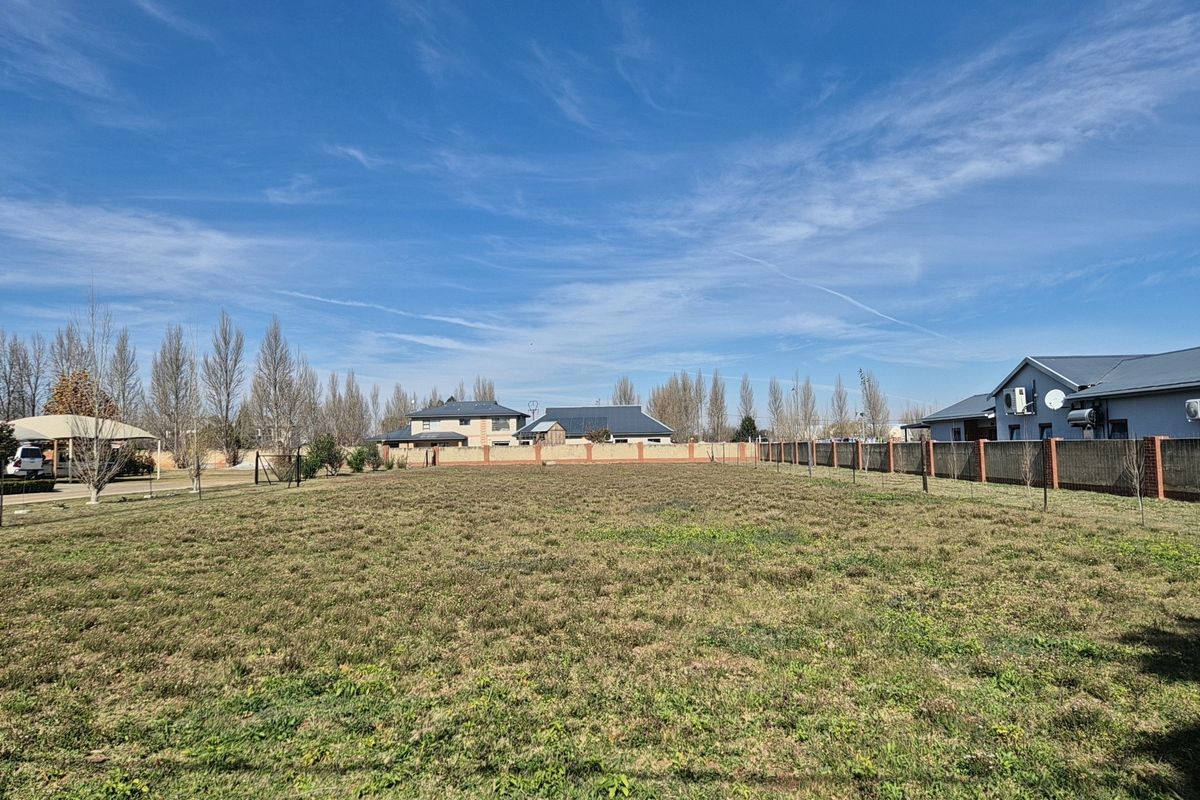 A level, vacant residential plot of land enclosed by perimeter boundary walls, situated in a developed neighborhood setting.