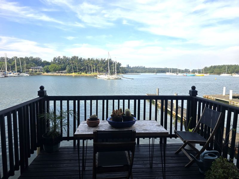 A wooden deck balcony featuring a dark timber balustrade, offering expansive views over the marina and waterfront.