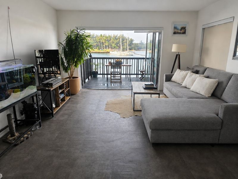 Open-plan living area featuring large bi-fold doors opening onto a private balcony with scenic water and marina views.