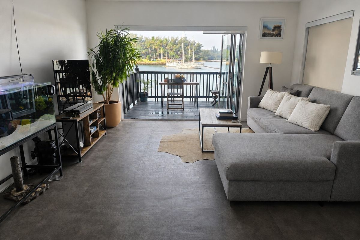 Open-plan living area featuring large bi-fold doors opening onto a private balcony with scenic water and marina views.