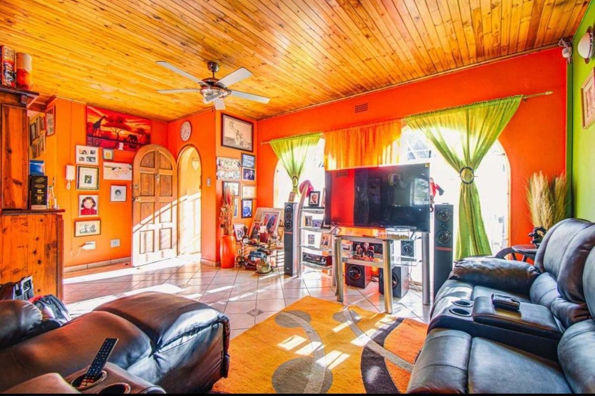A living room featuring a timber-clad ceiling, tiled flooring, and an arched doorway, providing a warm and rustic atmosphere.