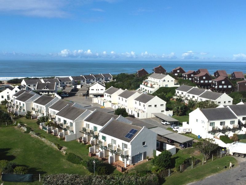 Aerial view of a coastal townhouse complex featuring multiple residential units, paved driveways, and proximity to the ocean.