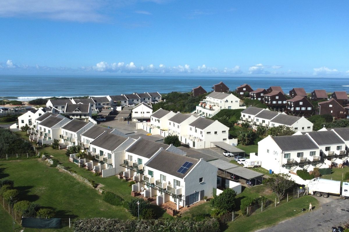Aerial view of a coastal townhouse complex featuring multiple residential units, paved driveways, and proximity to the ocean.