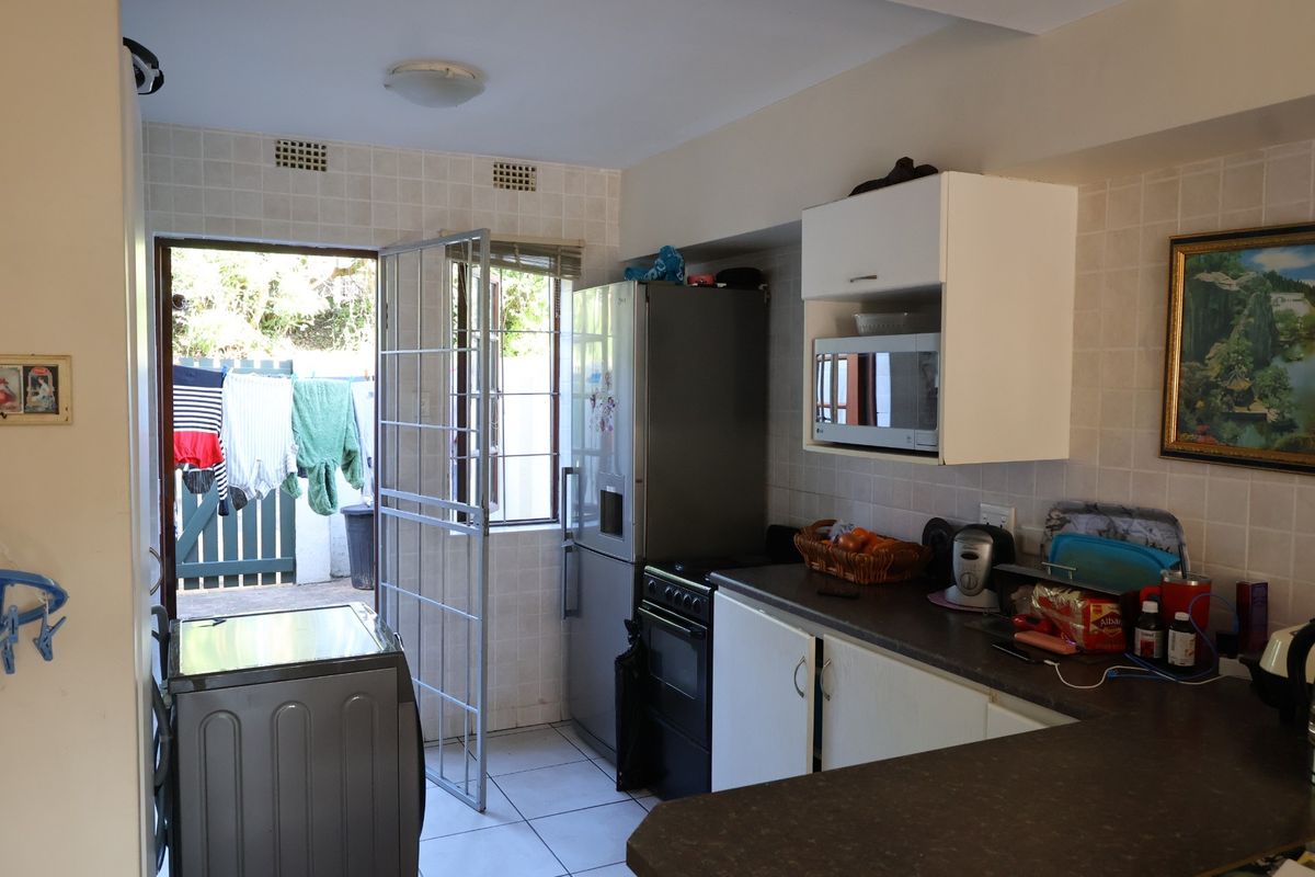 Functional kitchen area featuring tiled walls, built-in cabinetry, and direct access to an outdoor utility space.