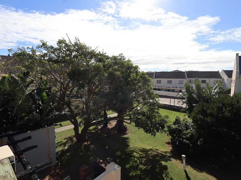 Elevated view overlooking a communal garden area with mature trees and surrounding townhouse architecture.