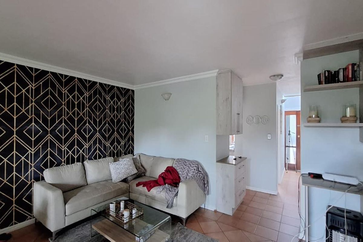 A living room featuring tiled flooring, built-in cabinetry, and a decorative feature wall, providing a functional and well-defined living space.