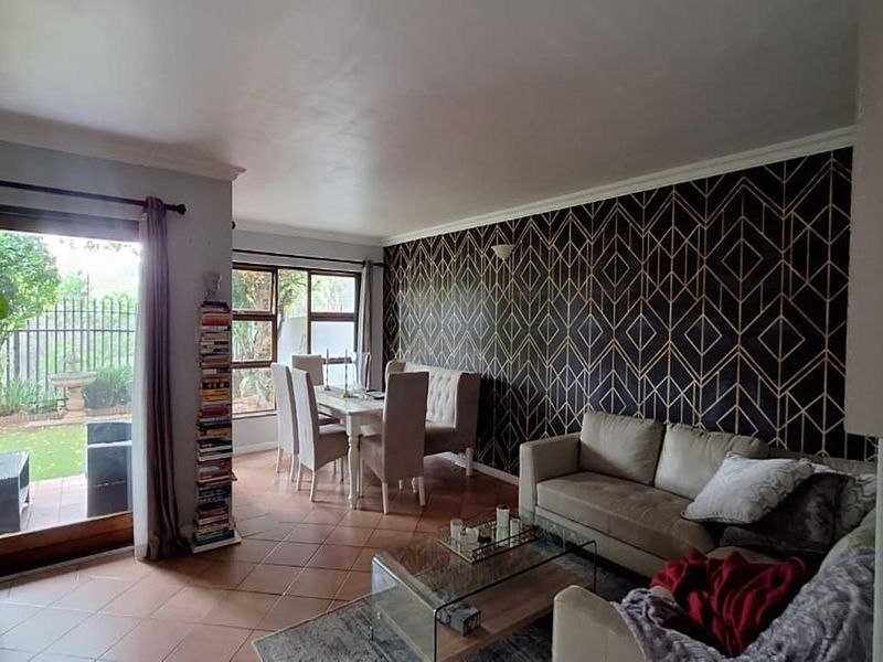 Open plan living and dining area featuring tiled flooring, decorative feature wall, and sliding glass doors providing access to the rear garden.