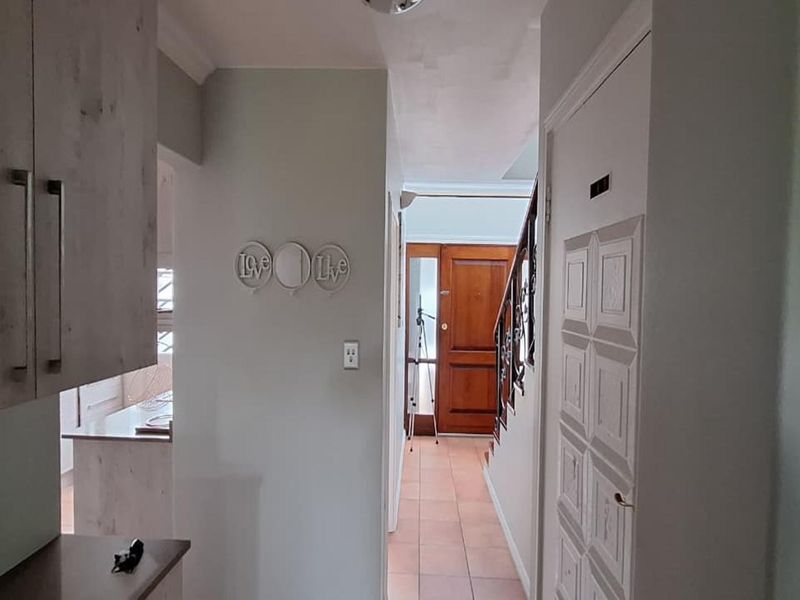 A bright hallway featuring tiled flooring, a wooden front door, and a staircase with a decorative wrought iron railing.