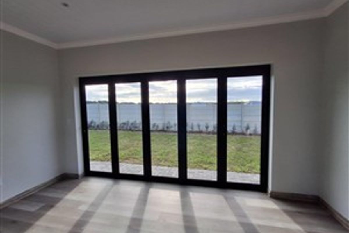 Bright living area featuring large black-framed stacker doors that open directly onto the rear garden, providing seamless indoor-outdoor flow.
