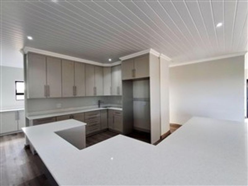 Modern kitchen featuring light-toned cabinetry, stone countertops, a U-shaped breakfast bar, and a tongue-and-groove ceiling with recessed lighting.