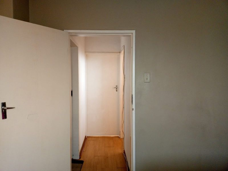 A view through an open doorway into a hallway featuring wood-look flooring and neutral wall finishes.